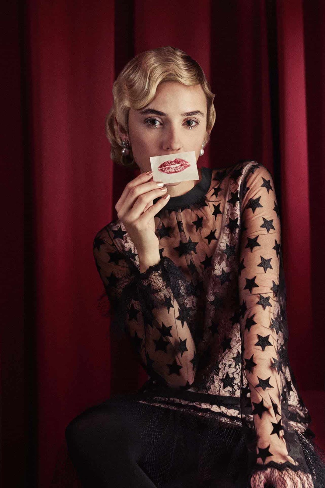 Portrait of a woman seated against a curtain, photographed by Oliver Doran